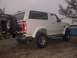 1994 Ford Bronco - This 1994 Ford Bronco is seen from the rear, parked on a gravel surface with trees and water in the background.